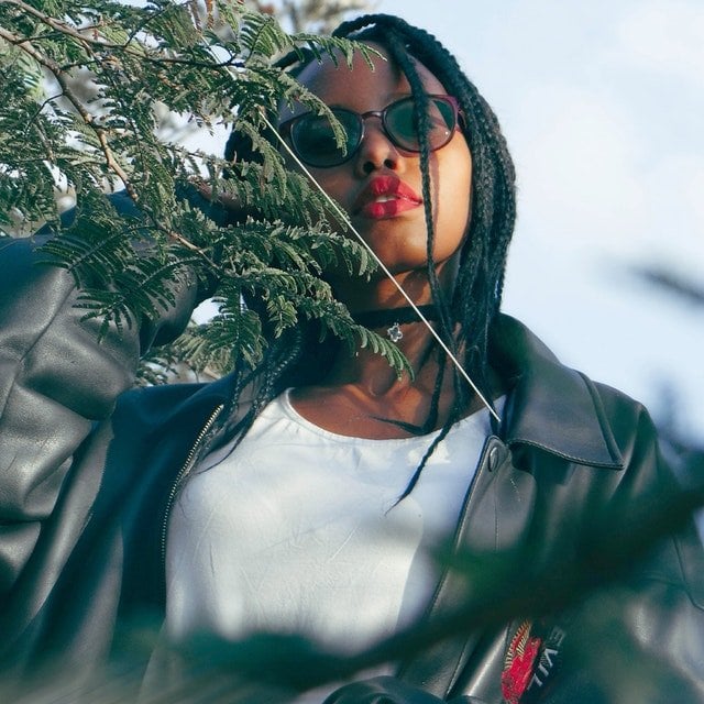 Young woman with braids wearing an oversized plus size black leather motorcycle jacket