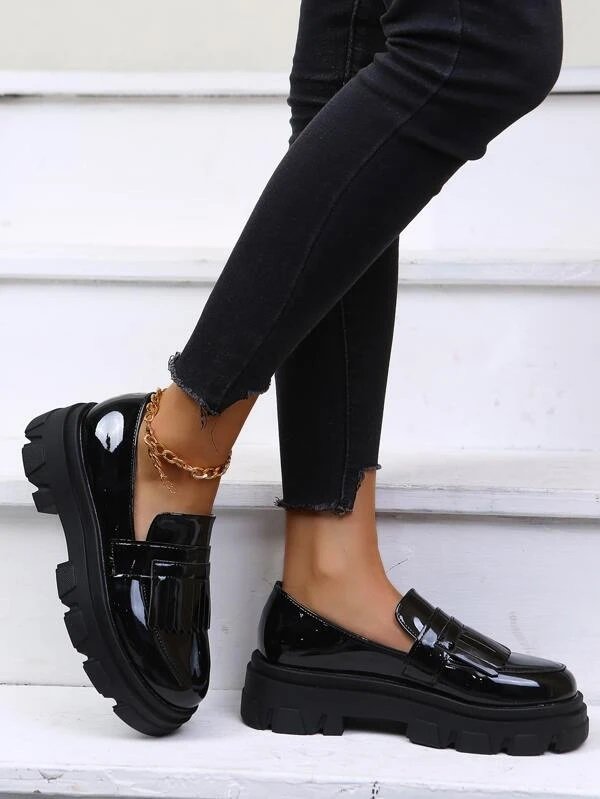 Black fringe platform loafers worn with black jeans