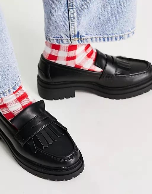 Black chunky loafers worn with jeans and red socks