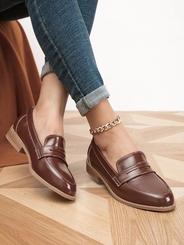 Brown flat loafers worn by a woman with an ankle bracelet