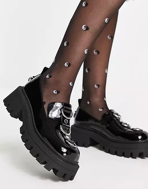 Black glossy chunky loafers with details worn with patterned tights