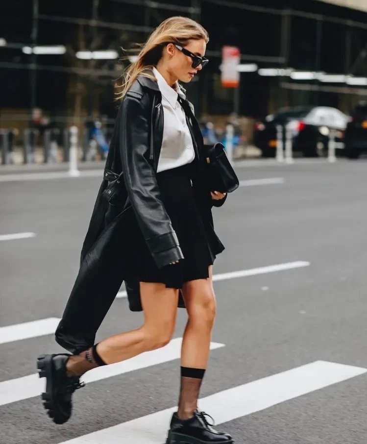 Black chunky loafers worn with a shirt and black skirt