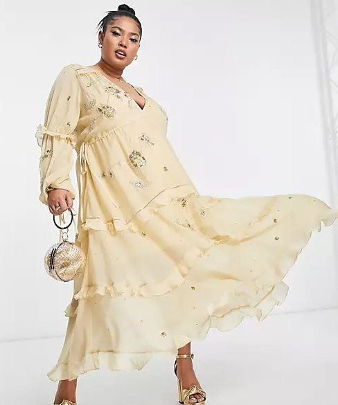 Curvy woman wearing a mid-length bohemian dress with long sleeves.