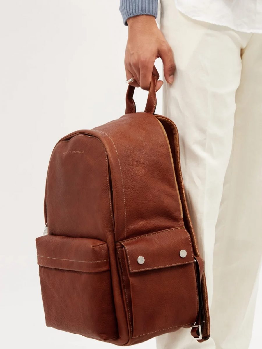 Dark brown textured leather backpack for men held by its handle