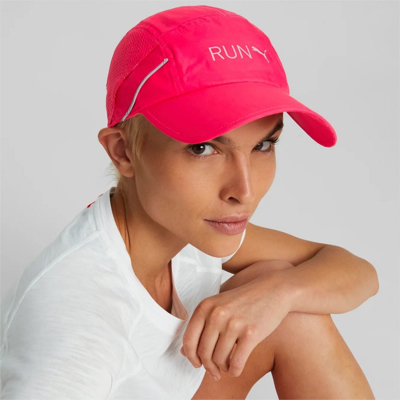 Woman wearing a fluo pink running cap from Puma