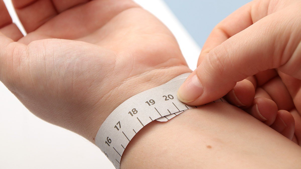 A woman measuring her wrist with a tape measure