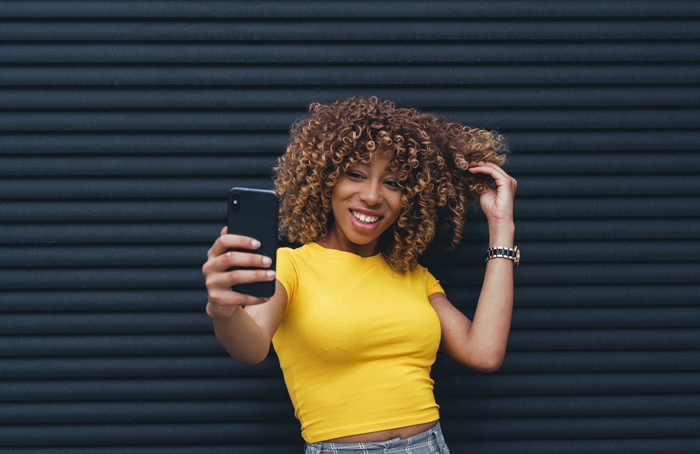 Woman wearing a yellow top taking a selfie