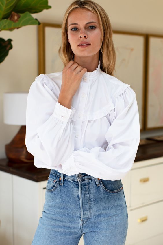 A woman wearing a white shirt bodysuit and jeans