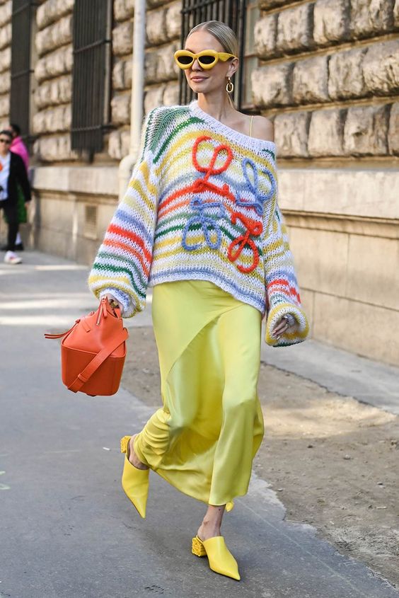 Woman wearing a knitted trunk over a dress in the street.