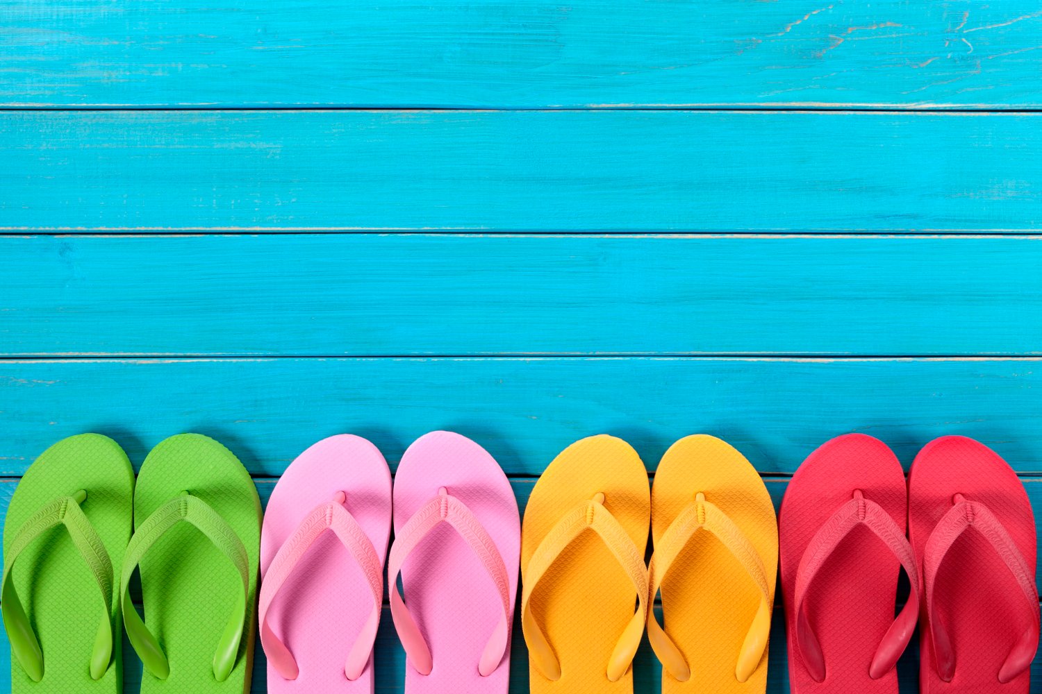 Different colored sandals lined up on a blue background